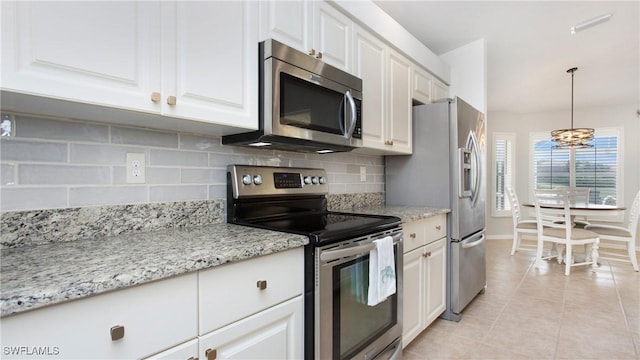 kitchen featuring light tile patterned floors, white cabinets, appliances with stainless steel finishes, hanging light fixtures, and backsplash