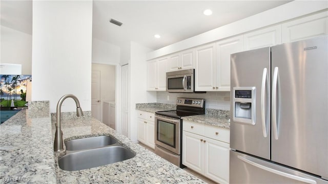 kitchen with visible vents, decorative backsplash, stainless steel appliances, washer and dryer, and a sink