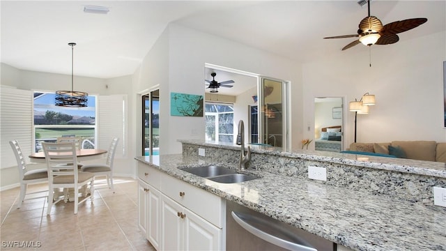 kitchen featuring light stone counters, light tile patterned flooring, a sink, visible vents, and hanging light fixtures