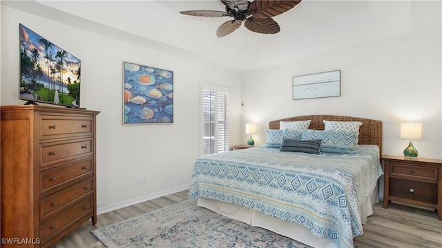 bedroom with a ceiling fan, light wood-type flooring, and baseboards