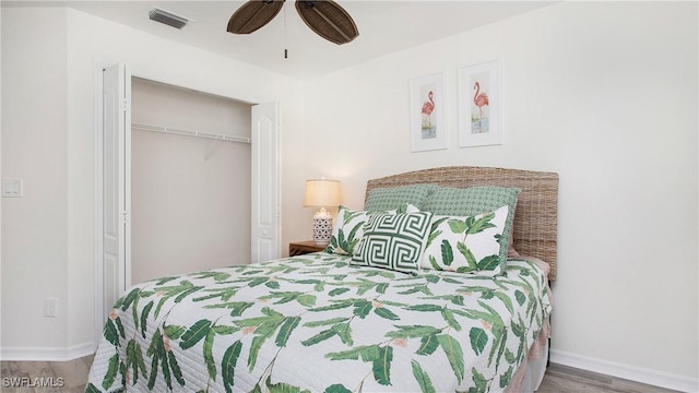 bedroom featuring wood finished floors, a ceiling fan, visible vents, baseboards, and a closet