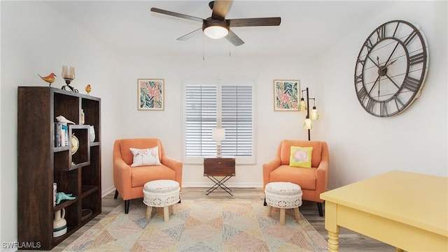 living area with ceiling fan, baseboards, and wood finished floors