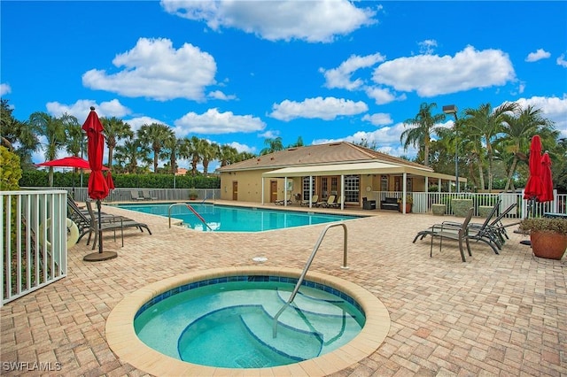 community pool featuring a hot tub, fence, and a patio