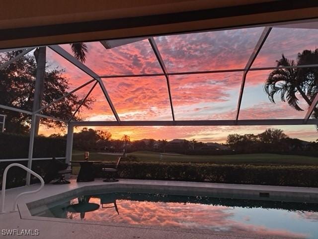 pool at dusk with an outdoor pool, glass enclosure, and a patio