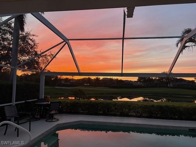 pool at dusk with a lanai, a patio area, and an outdoor pool