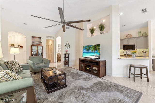 living area featuring light tile patterned flooring, visible vents, arched walkways, and ceiling fan