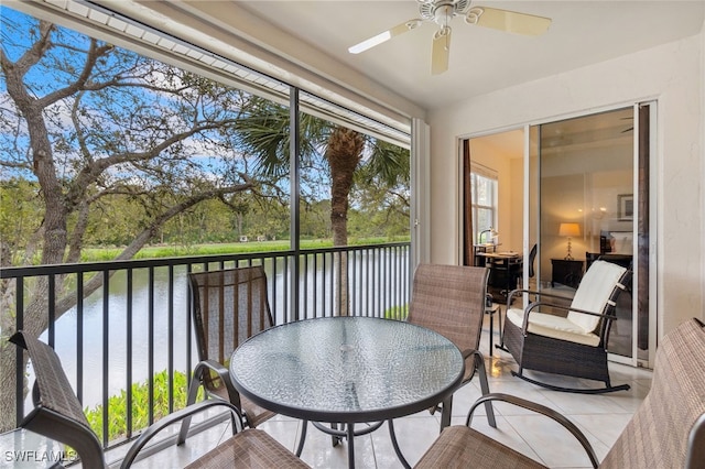 sunroom / solarium featuring a water view and ceiling fan