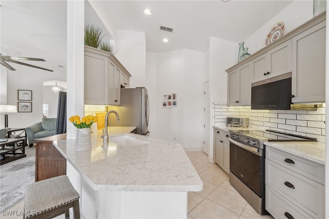 kitchen featuring decorative backsplash, appliances with stainless steel finishes, light stone countertops, and a sink