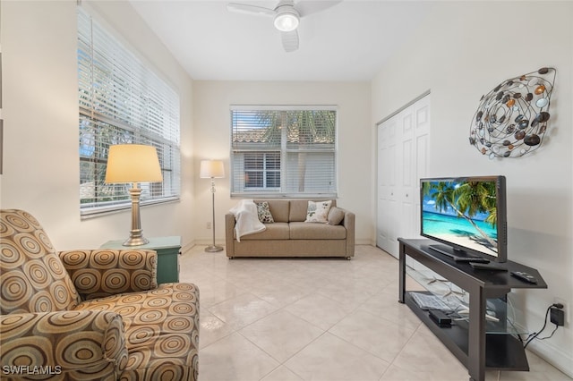 living room featuring light tile patterned floors, baseboards, and ceiling fan