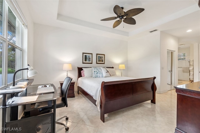 bedroom featuring a tray ceiling, visible vents, a ceiling fan, and light tile patterned floors