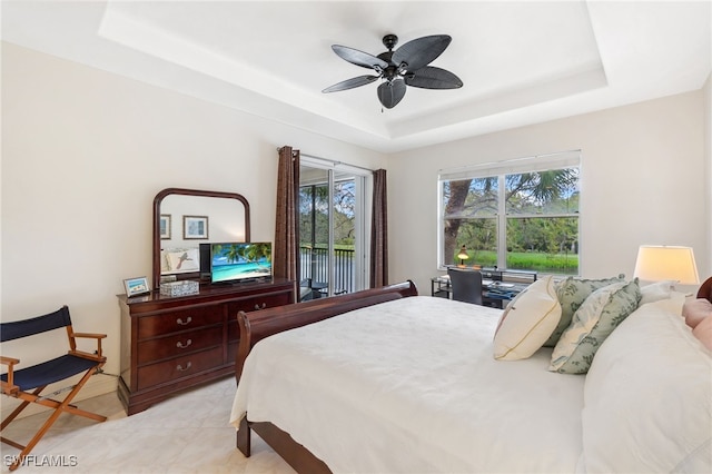 bedroom with a tray ceiling, access to outside, light tile patterned floors, and ceiling fan