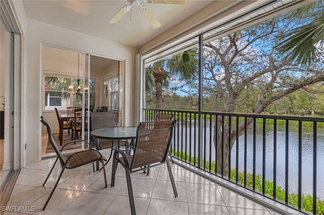 sunroom / solarium featuring ceiling fan with notable chandelier and a water view