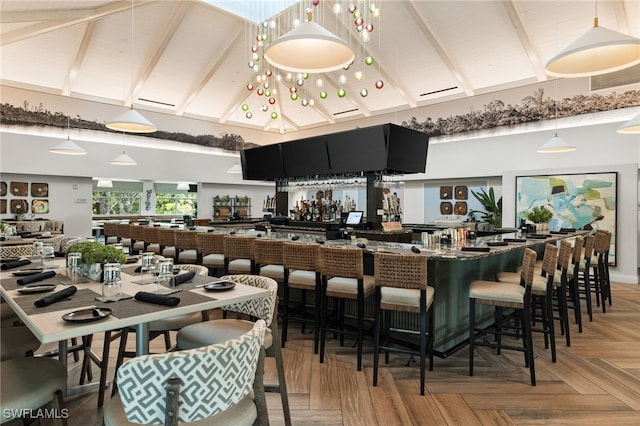 bar with decorative light fixtures, beamed ceiling, and high vaulted ceiling