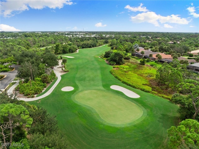 drone / aerial view with view of golf course and a wooded view