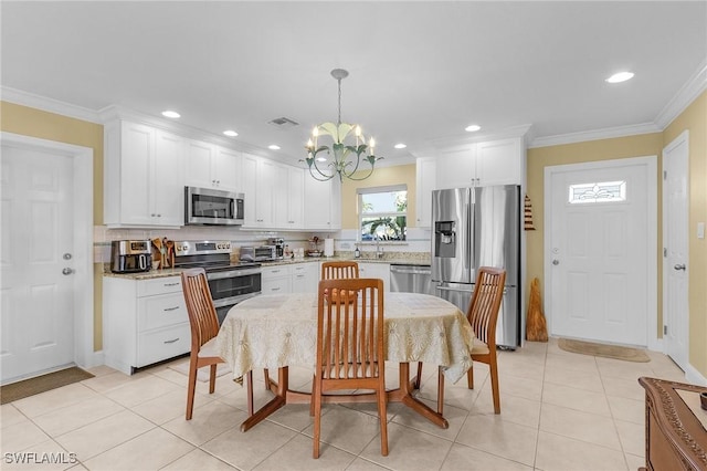 kitchen featuring an inviting chandelier, stainless steel appliances, white cabinets, visible vents, and backsplash