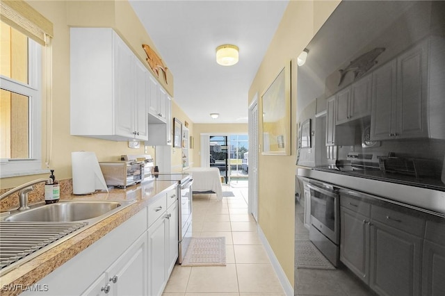 kitchen featuring light countertops, white cabinets, light tile patterned flooring, and stainless steel electric range