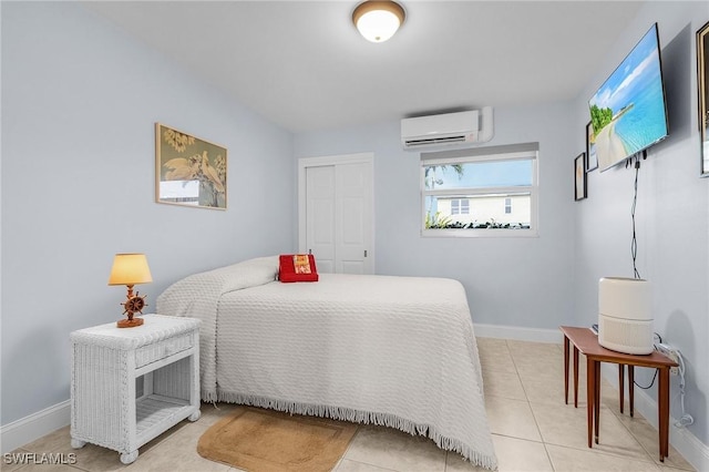 bedroom with a closet, light tile patterned flooring, baseboards, and a wall mounted air conditioner