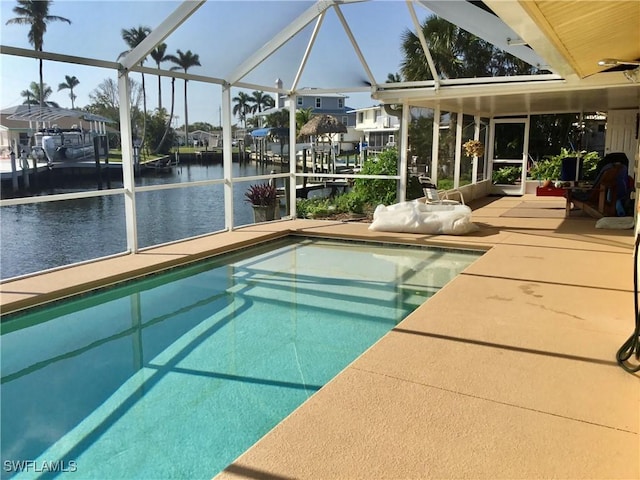 pool with glass enclosure, a patio, and a water view