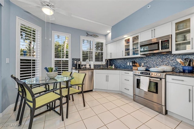 kitchen with appliances with stainless steel finishes, dark countertops, a sink, and decorative backsplash