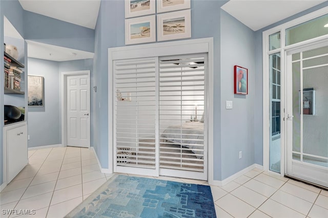 entryway with lofted ceiling, light tile patterned floors, and baseboards