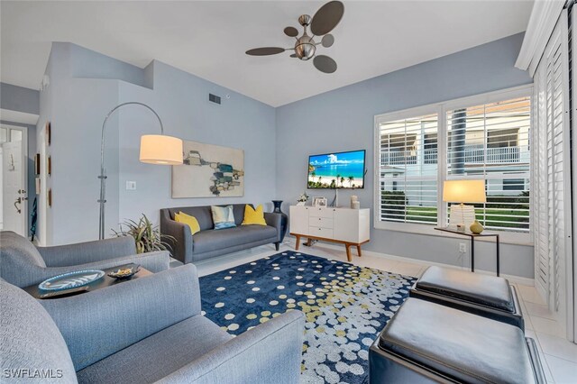 living room featuring tile patterned flooring, visible vents, ceiling fan, and baseboards