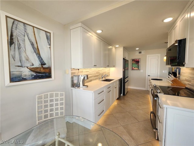 kitchen with black appliances, visible vents, white cabinets, and backsplash