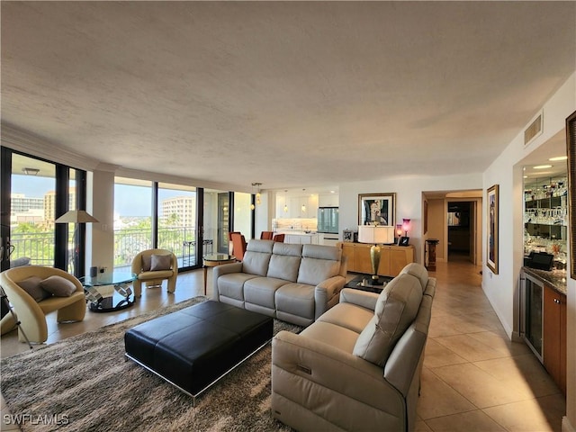 living area featuring expansive windows, visible vents, a textured ceiling, and light tile patterned floors