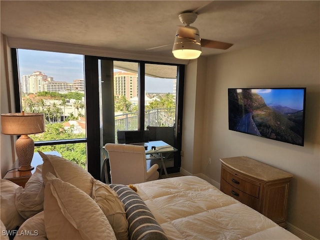 bedroom featuring a ceiling fan, baseboards, and a city view