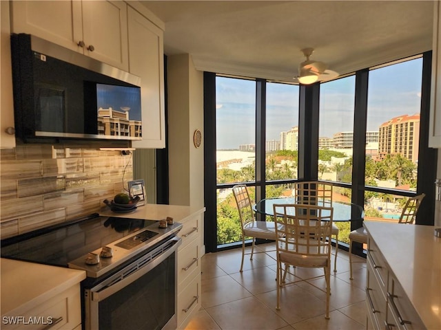 kitchen featuring a view of city, light countertops, backsplash, stainless steel electric range oven, and a wall of windows