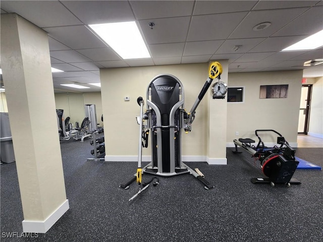 gym featuring a paneled ceiling and baseboards