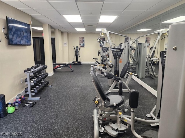 gym featuring a paneled ceiling and baseboards