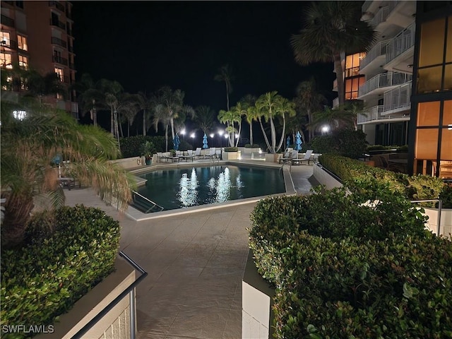 pool at twilight with a patio and a community pool