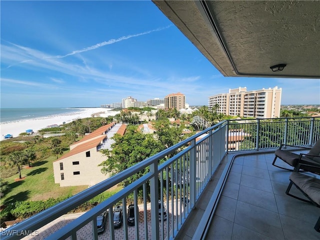 balcony featuring a view of city, a water view, and a beach view