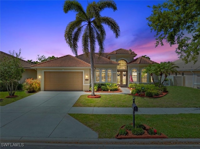 mediterranean / spanish-style home featuring concrete driveway, a yard, french doors, and stucco siding