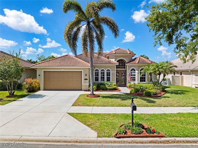 mediterranean / spanish-style house featuring a tile roof, driveway, a front lawn, and stucco siding