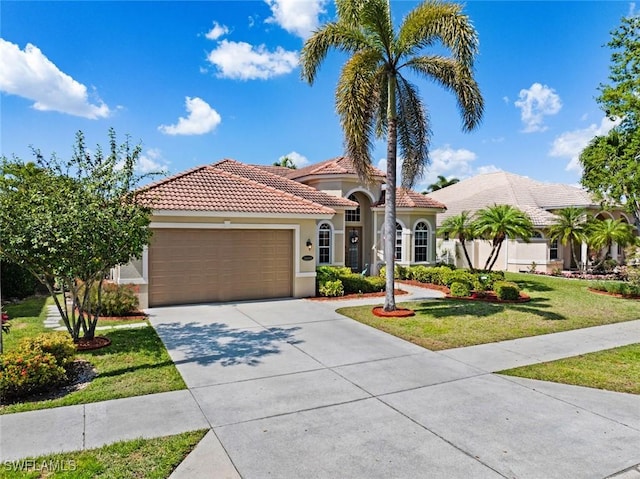 mediterranean / spanish-style house featuring stucco siding, an attached garage, driveway, a tiled roof, and a front lawn