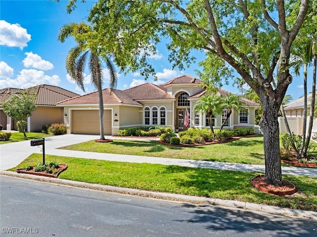 mediterranean / spanish-style home featuring a garage, driveway, a tiled roof, stucco siding, and a front yard