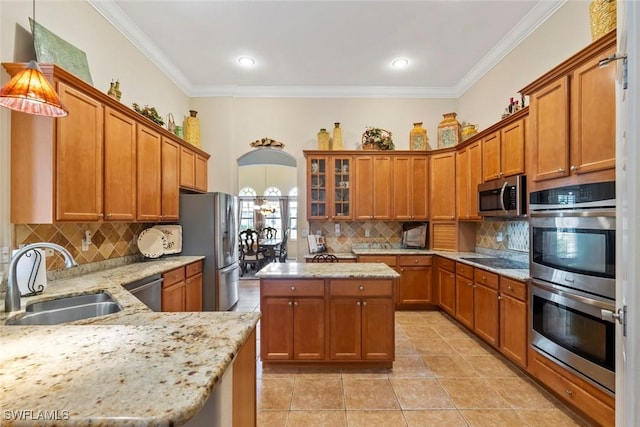 kitchen featuring brown cabinetry, light stone counters, stainless steel appliances, and a sink