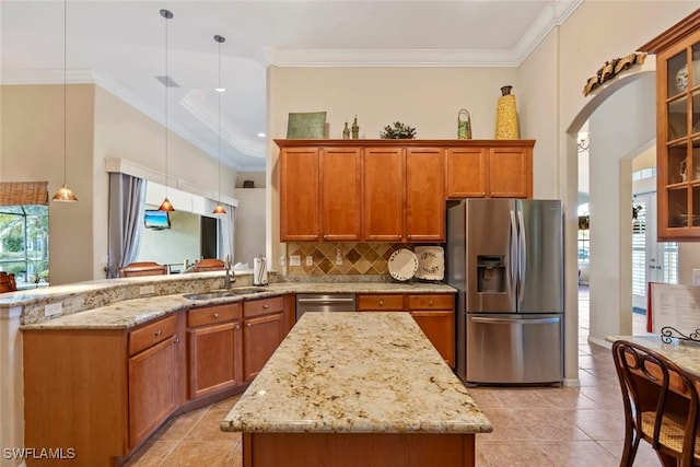 kitchen with stainless steel appliances, a peninsula, a sink, ornamental molding, and brown cabinets