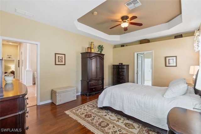 bedroom featuring dark wood-style flooring, a raised ceiling, and visible vents