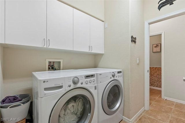 laundry area with washer and clothes dryer, light tile patterned flooring, cabinet space, and baseboards