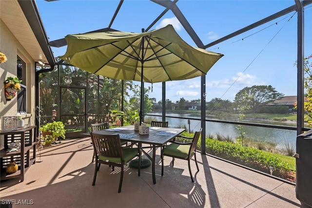 view of patio featuring a water view, glass enclosure, and outdoor dining area