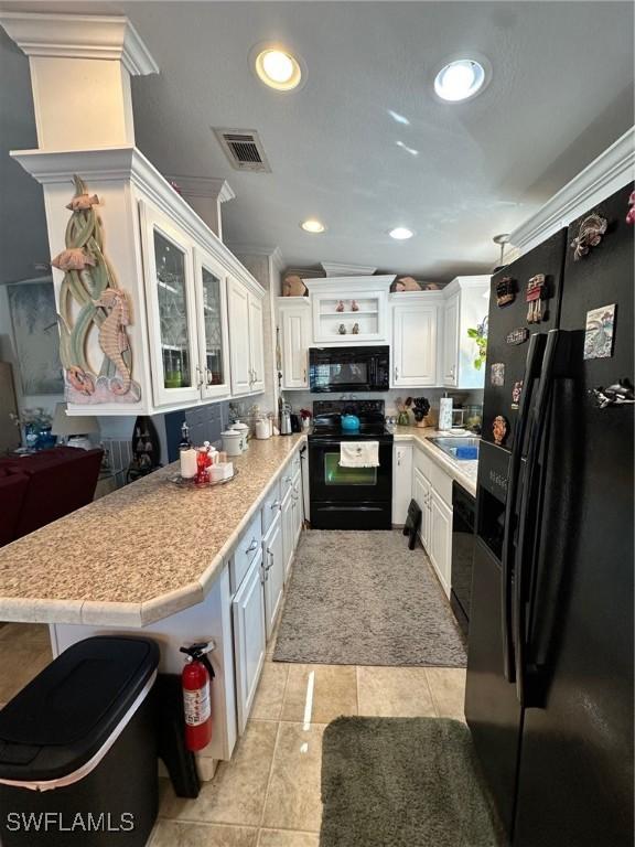 kitchen with visible vents, black appliances, white cabinetry, light countertops, and glass insert cabinets