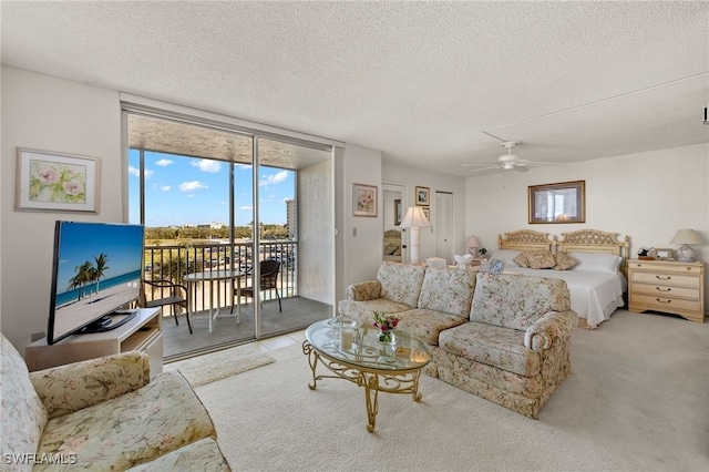 carpeted bedroom with access to exterior, a textured ceiling, ceiling fan, and expansive windows