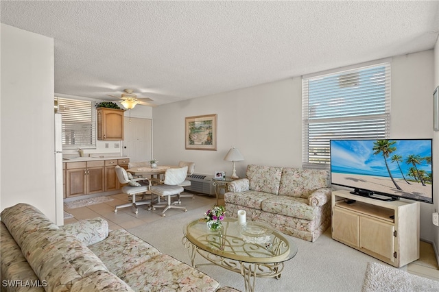 living room featuring light tile patterned floors, a ceiling fan, and a textured ceiling