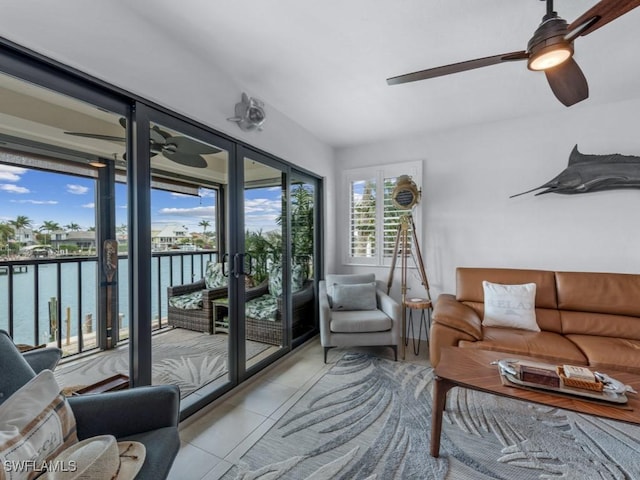 tiled living room with french doors, a water view, and ceiling fan