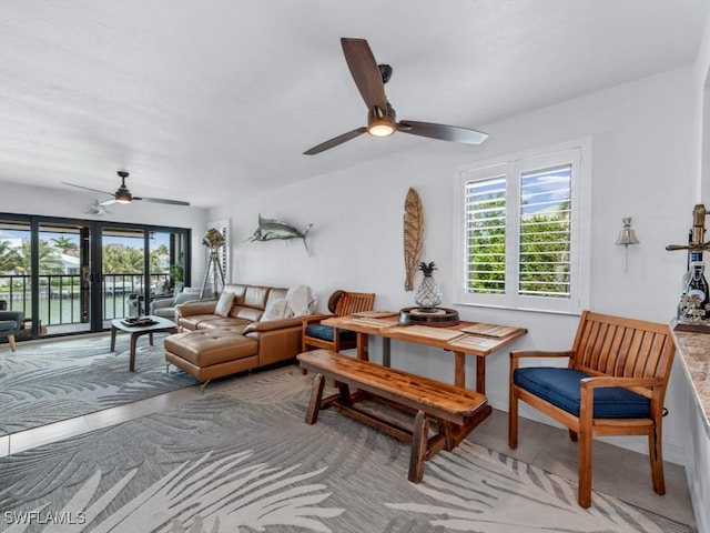 living area with a ceiling fan and light tile patterned floors