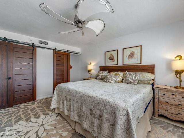 bedroom with a barn door, visible vents, and a ceiling fan