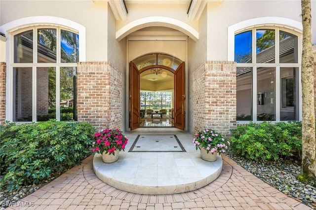 doorway to property featuring brick siding and stucco siding