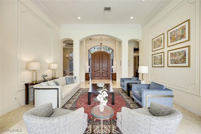 living area with baseboards, visible vents, arched walkways, and ornamental molding